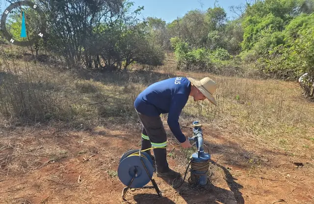 Medidor de nível elétrico sendo descido na boca de um poço tubular em propriedade rural de Goiás